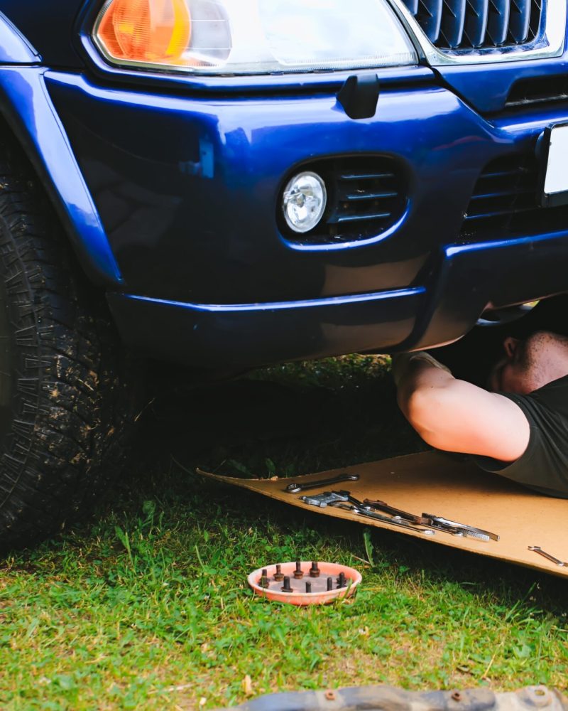 man repairs a car on the street lying on the grass. Russia Moscow 15.06.2019
